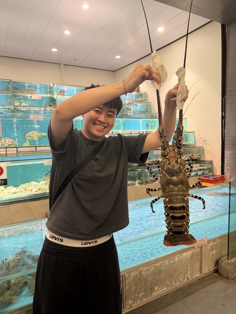 Han Long grinning, holding up a giant live lobster at the seafood tanks