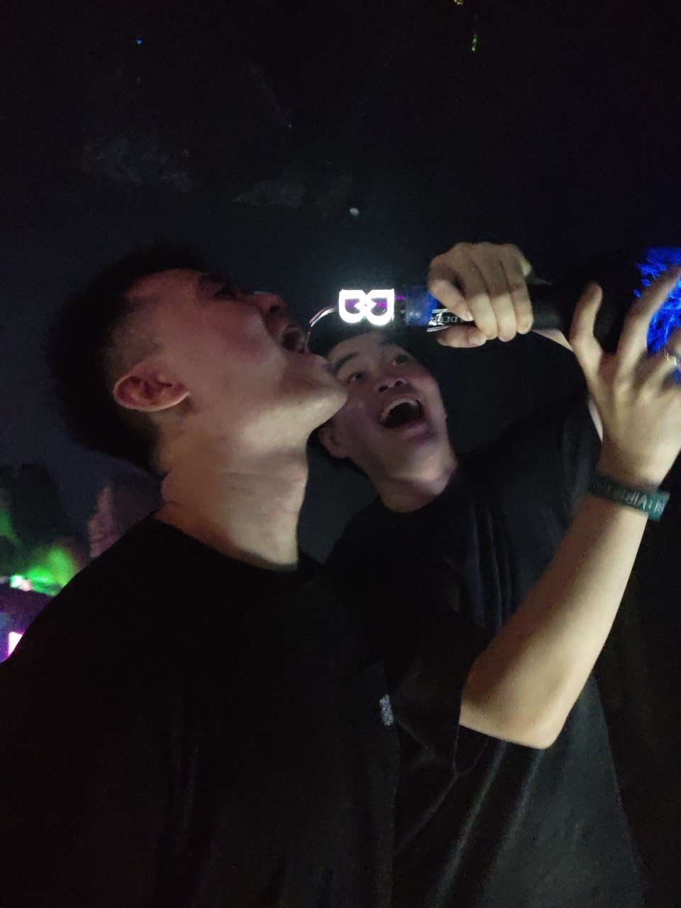 The crew sharing a bottle on the club dancefloor under neon light