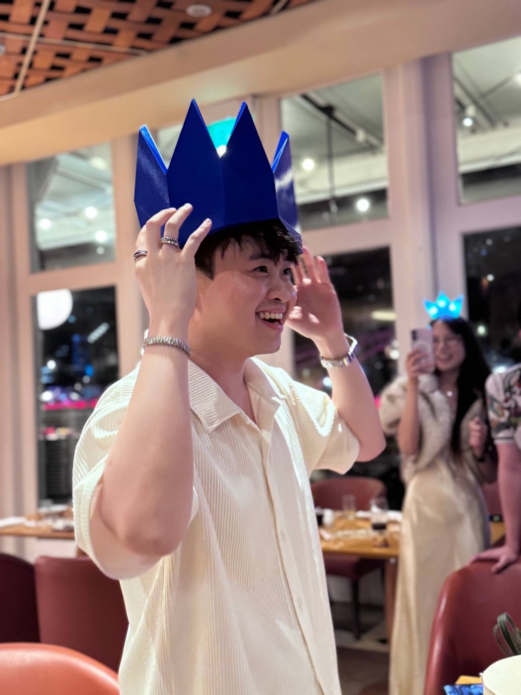 Han Long grinning as he lifts his blue LED crown at his birthday dinner